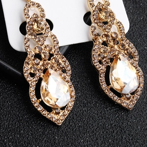 Close-up of golden vintage drop earrings with champagne rhinestones and pear-cut crystal