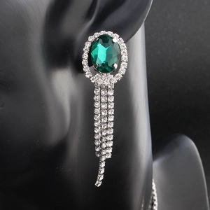 Dettaglio di orecchini pendenti argento con smeraldi verdi e nappe in strass lucidi