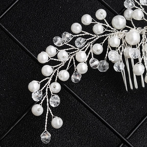 Close-up of handmade bridal hair comb with silver wire, white pearls and crystal beads
