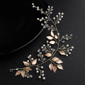 Macro view of bridal hair vine with gold leaves, pearls and crystal beads on black background