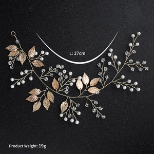 Handmade bridal hair vine with pearls, crystals, and gold leaves on a black surface