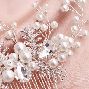 Macro shot of silver bridal hair comb with pearls and teardrop crystal on pink silk