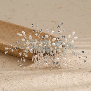 Elegant bridal hair comb with pearls and rhinestones on a rustic wooden stand