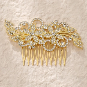 Close-up of golden bridal hair comb with floral rhinestone patterns and metal teeth