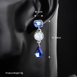 Detailed view of luxury bridal drop earrings with blue marquise crystals on a model ear