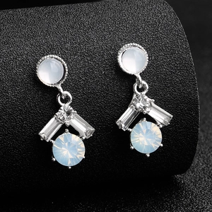 Close-up of vintage bridal drop earrings with opal-like stones and crystals on a black stand