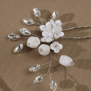 Détail de l'épingle à cheveux fleur en céramique blanche avec cristaux et fils d'argent