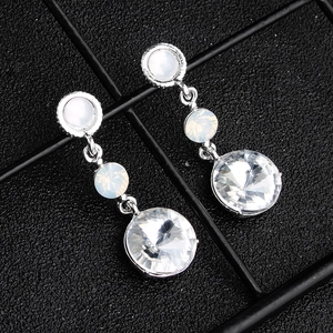 Detail of luxury bridal earrings with three-tiered crystals on a black mesh background