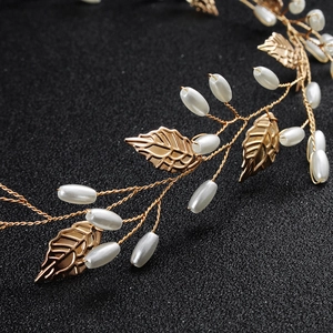 Macro detail of hand-woven gold leaves and white teardrop pearls bridal hairpiece
