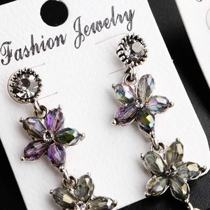 Macro detail of vintage floral drop earrings with colorful crystals and silver alloy base