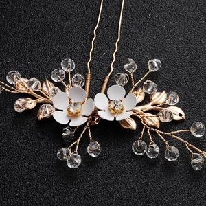 Detailed macro view of handmade bridal hair pins featuring white flowers and gold leaves