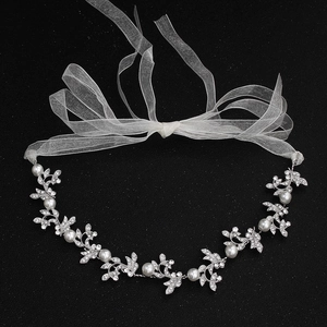 Gros plan d'un bandeau de mariée avec feuilles argentées, strass et perles blanches d'imitation