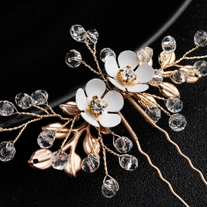 Detail of bridal hair pin set with white enamel flowers, gold leaves and crystal beads