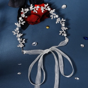 Détail macro du bandeau de mariée avec feuilles en argent, perles et strass sur tissu bleu