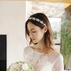 Close-up of white resin floral bridal headband with faux pearls and silver alloy leaf details