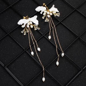 Elegante Brautohrringe mit langen Quasten, weißen Perlen und Blütenblättern auf dunklem Grund