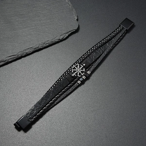 Détail d'un bracelet multicouche en cuir noir pour homme avec un charme en métal roue solaire