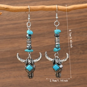 Detail view of Bohemian bull head earrings with turquoise beads hanging on a branch