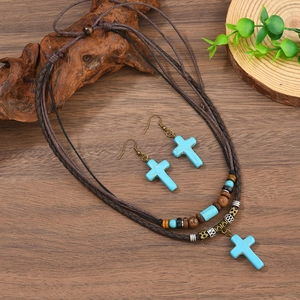 Détail du pendentif croix en turquoise bohème avec cordon en cuir tressé et perles en bois