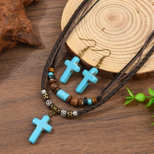 Détail d'un ensemble bijoux croix turquoise avec cuir tressé et perles de bois