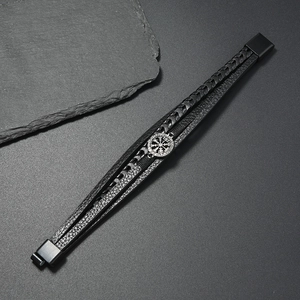 Macro detail of men's layered leather bracelet featuring a silver Viking compass metal charm