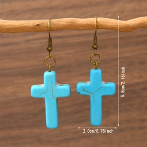 Detail shot of bohemian cross earrings with turquoise stones on rustic wood display