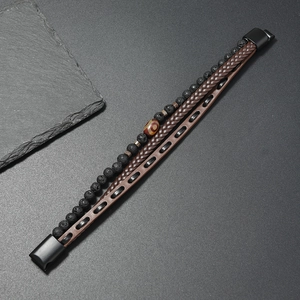 Detail of men's layered leather bracelet featuring lava stone beads and a magnetic clasp