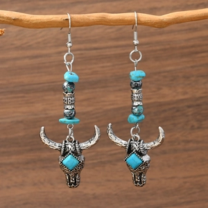 Bohemian turquoise drop earrings featuring a detailed cow skull pendant on a branch