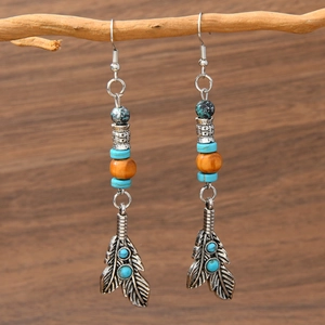 Vintage bohemian turquoise feather earrings featuring tribal silver engraving and wood beads