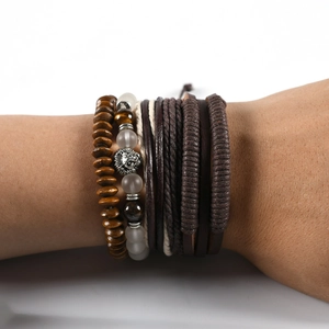 Close-up of layered leather bracelet with lion head charm and natural wood beads