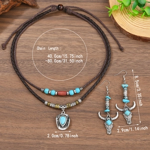 Gros plan sur collier bohème cowboy avec pendentif chapeau et boucles d'oreilles crâne de buffle