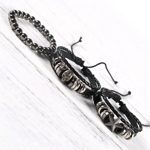 Detail of beaded metal bracelet and woven leather wristbands with skull and star charms