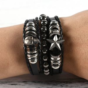 Detail of multi-layer leather bracelet featuring silver skull and star charms in punk style