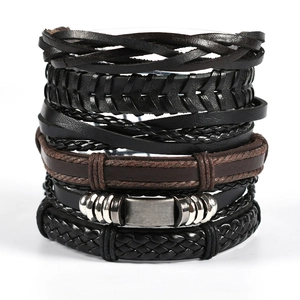 Close-up of stacked multi-layer leather bracelets with owl wing metal charms in punk style