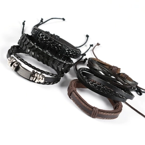 Detail of multi-layer woven leather bracelets with owl wing charms and punk metal tubes