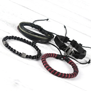 Detail of four-piece men's bracelet set with black leather, beads and metal wing charms