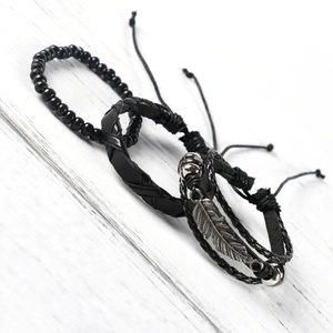 Detail of vintage black leather bracelet set with feather charm and bead accents