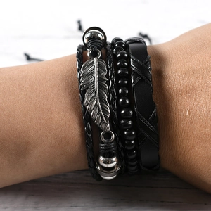 Detail of vintage layered black leather bracelets with silver feather and beads charms