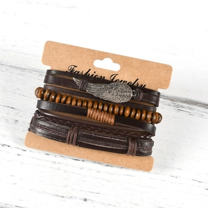 Detailed macro of layered leather bracelet with silver wing charm and wood beads on card