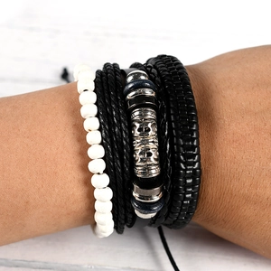 Detail of a punk style multi-layer bracelet with skull charm and leather braid wristband