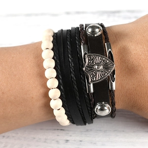 Detail of vintage stackable leather bracelet set with wooden beads and metal shield charm