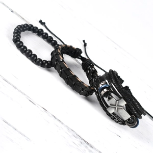 Detail of men's black leather wristband set with matte beads and vintage metal cross charm