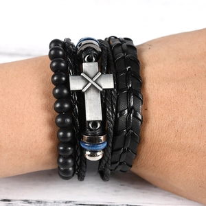 Detail of multi-layer leather bracelet featuring black beads and a vintage silver cross charm