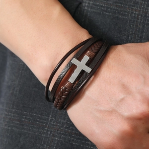Detailed close-up of a men's multi-layer leather bracelet with silver cross and magnet clasp