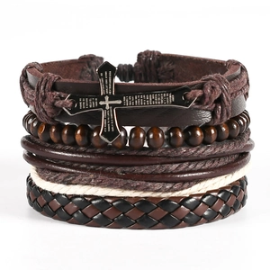 Detail of layered leather bracelet featuring engraved metal cross and wooden beads