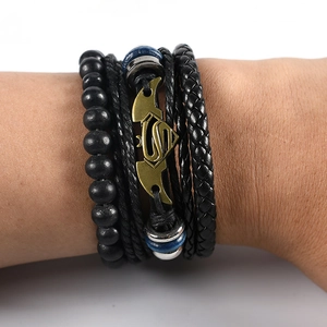 Close-up of multilayer leather bracelet featuring a bronze Superman logo charm