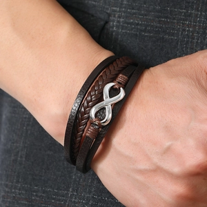 Close-up of men's leather infinity bracelet with silver metal buckle on a suit sleeve