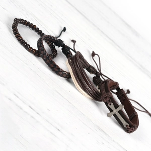 Detail shot of multi-layer leather bracelets with vintage cross and wooden beads