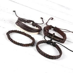 Close-up of retro leather bracelets with wooden beads and silver cross pendant detail