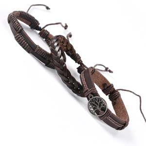Macro detail of retro brown leather woven bracelets with tree of life metal pendant